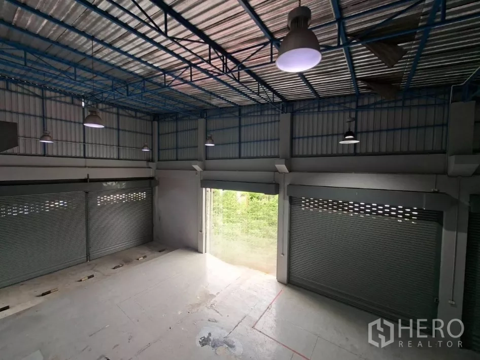 Warehouse for rent in Suan Luang, Bangkok - Overhead view of steel‑truss roof with industrial pendant lights and ventilation panels.