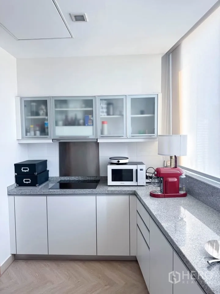 คอนโด for rent or sale in Khlong Toei, Bangkok - ครัวมุมพร้อมตู้กระจก เตาอินดักชัน ไมโครเวฟ และอุปกรณ์เครื่องใช้ไฟฟ้า.