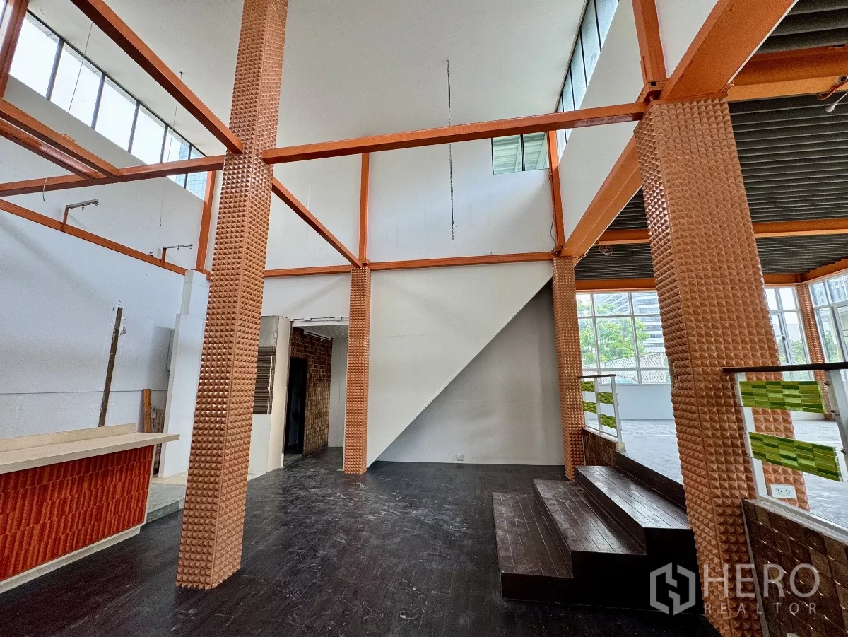 Shophouse for rent in Sathon, Bangkok - Open-plan shophouse interior with high ceiling, short steps and large windows.