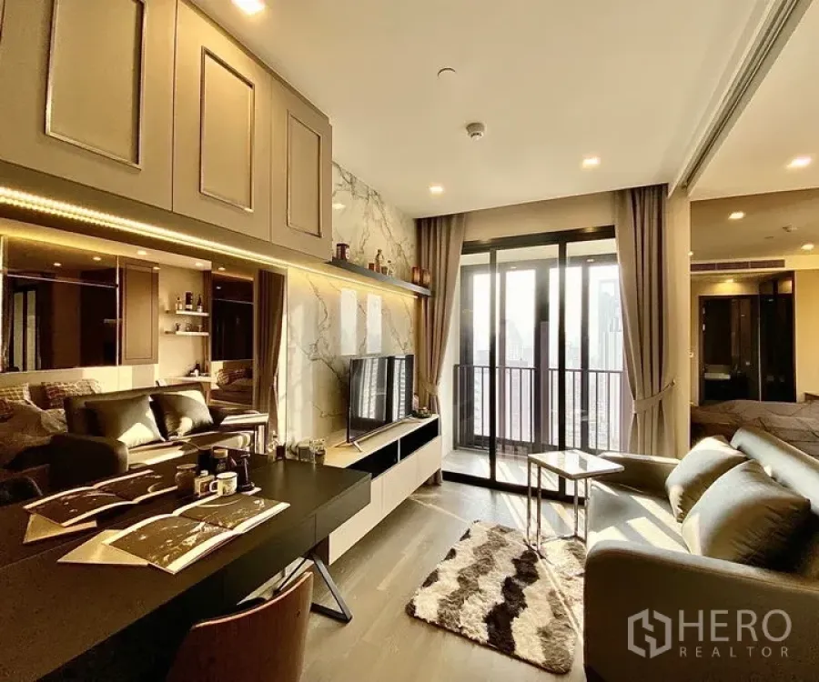 คอนโด ให้เช่าในWatthana, Bangkok - ห้องนั่งเล่นสว่าง ผนังทีวีลายหินอ่อน ชั้นบิวท์อิน โต๊ะทำงาน และประตูกระจกออกสู่ระเบียงวิวเมือง