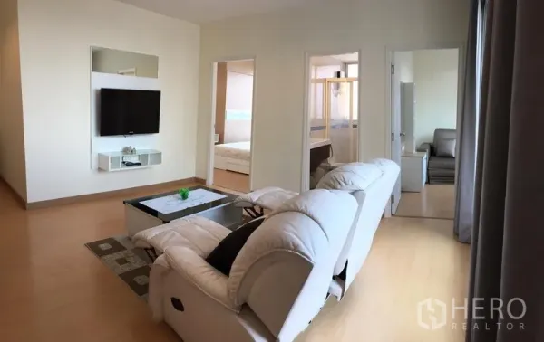 คอนโด ให้เช่าในWatthana, Bangkok - อีกมุมของห้องนั่งเล่น โซฟาหันหน้าไปทางทีวี พื้นไม้ และผนังกระจกเต็มบาน