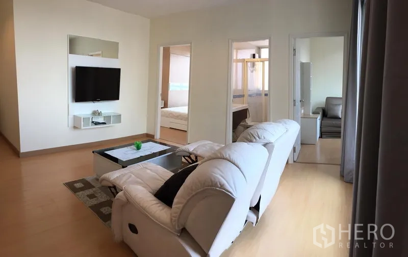 คอนโด ให้เช่าในWatthana, Bangkok - อีกมุมของห้องนั่งเล่น โซฟาหันหน้าไปทางทีวี พื้นไม้ และผนังกระจกเต็มบาน