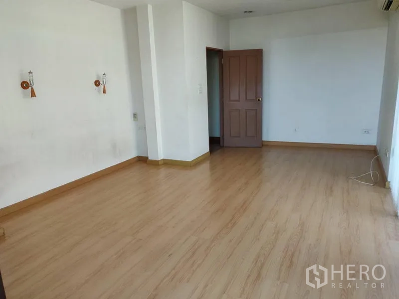 Home Office for rent in Watthana, Bangkok - Spacious bedroom with wood floors and doorway to an adjoining room.