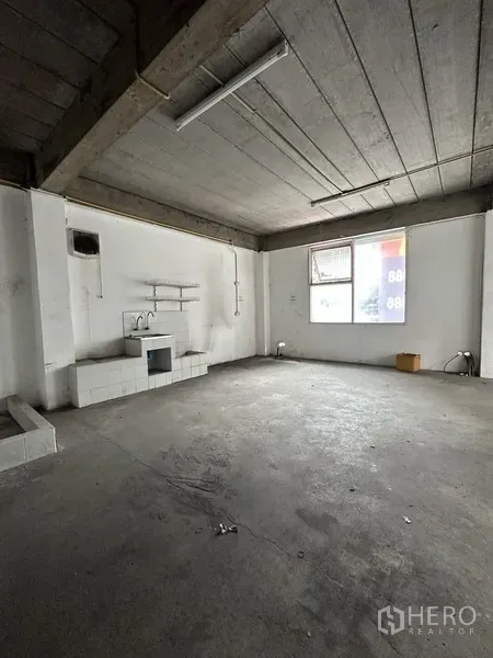 零售空间 出租在Khlong Toei, Bangkok - 未装修的水泥零售区，带水槽和置物架，裸露天花与窗户。