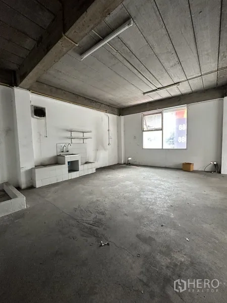 零售空间 出租在Khlong Toei, Bangkok - 未装修的水泥零售区，带水槽和置物架，裸露天花与窗户。