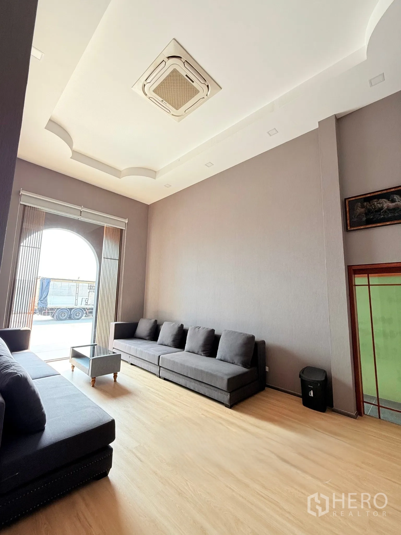 Factory for sale in Ban Bueng, Chon Buri - Bright office lounge with gray sofas, window blinds, and light wood floor.