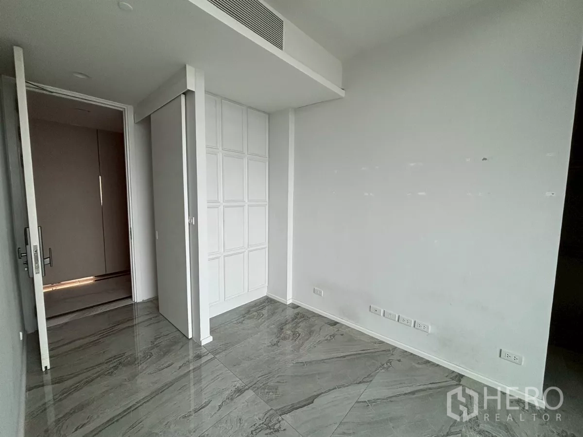 Condominium for sale in Bang Kho Laem, Bangkok - Empty room with white paneled wall, sliding door and glossy grey marble flooring with multiple power outlets.