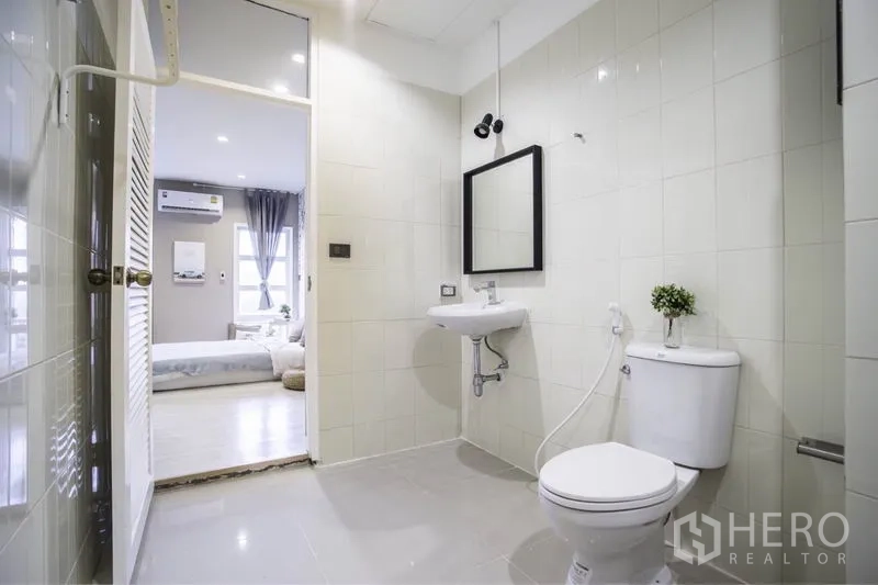 ทาวน์เฮาส์ ให้เช่าในKhlong Toei, Bangkok - ห้องน้ำกระเบื้องสีขาวสว่าง กระจก อ่างล้างหน้า และโถสุขภัณฑ์ เปิดสู่ห้องนอน