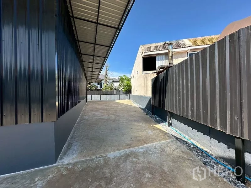 Warehouse for rent in Wang Thonglang, Bangkok - Side driveway beside the warehouse with canopy roof and fencing, allowing easy truck access and parking.