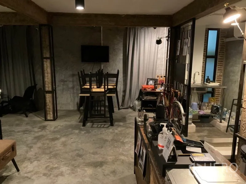 带办公室的家 出租在Phaya Thai, Bangkok - 工业风工作区，混凝土地面、灰色窗帘，桌上叠放椅子，自行车区与带水槽的小茶水间。