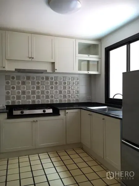 联排别墅 出租在Watthana, Bangkok - L形厨房，白色橱柜、花纹墙砖与窗户。