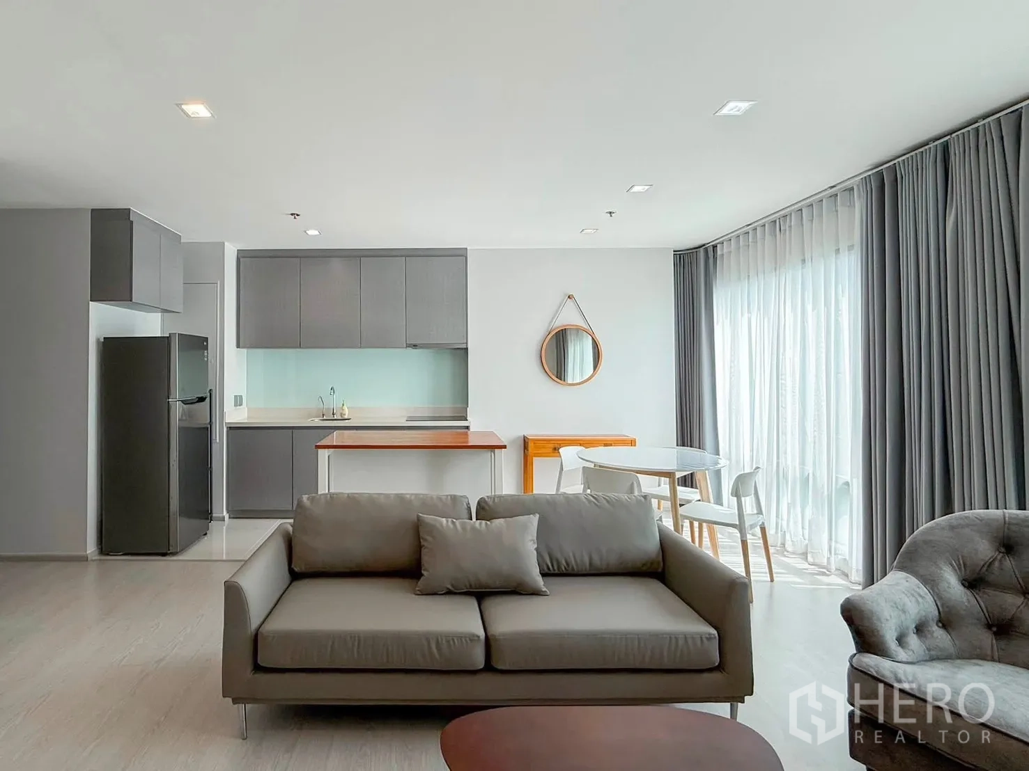 Condominium for rent in Khlong Toei, Bangkok - Open-plan lounge with sofa facing modern kitchen and dining area.