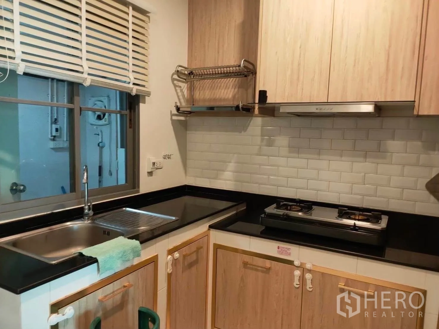 บ้านเดี่ยว for rent in Bang Phli, Samut Prakan - ครัวขนาดกะทัดรัด เตาแก๊ส เครื่องดูดควัน ท็อปหินสีดำ และผนังกระเบื้องซับเวย์สีขาว