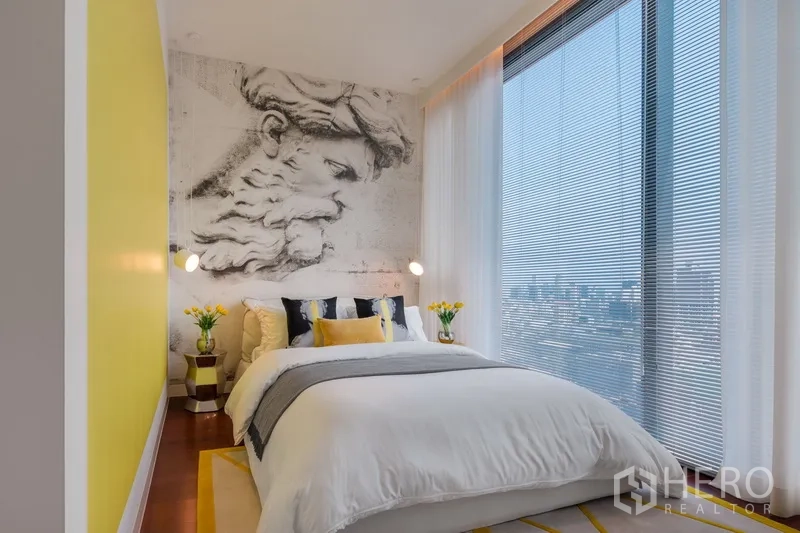 Condominium for sale in Watthana, Bangkok - Guest bedroom with yellow accent wall, mural and panoramic city‑view window.