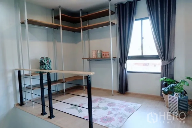 Townhouse for rent in Khlong Toei, Bangkok - Loft-style storage area with open shelving system, railing and window with curtains.