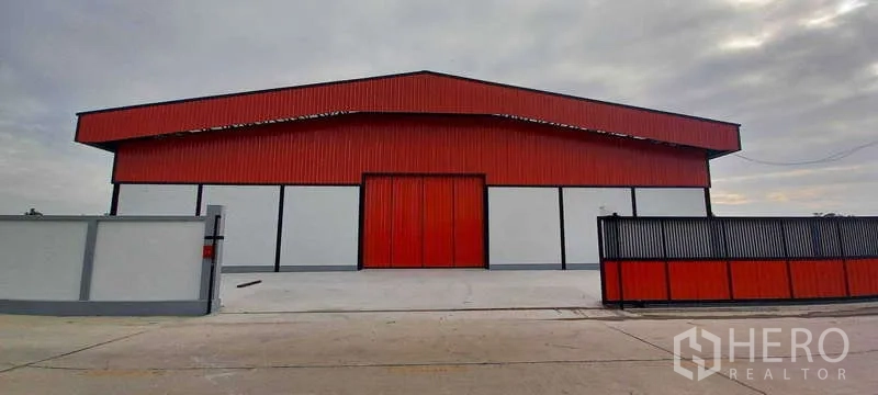 货栈 出租或出售在Khlong Luang, Pathum Thani - 白天立面，红白配色仓库，带大门入口、高屋顶与混凝土前场。