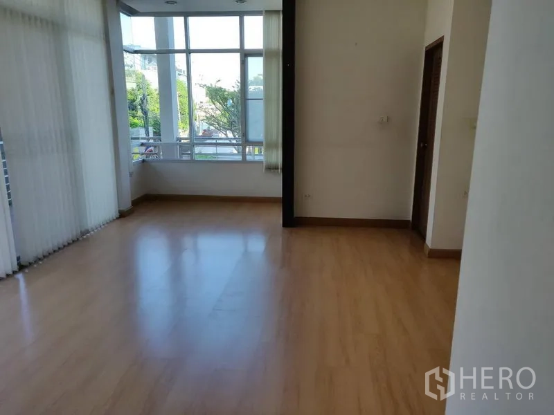 Home Office for rent in Watthana, Bangkok - Upper floor room with corner windows and warm wood flooring.