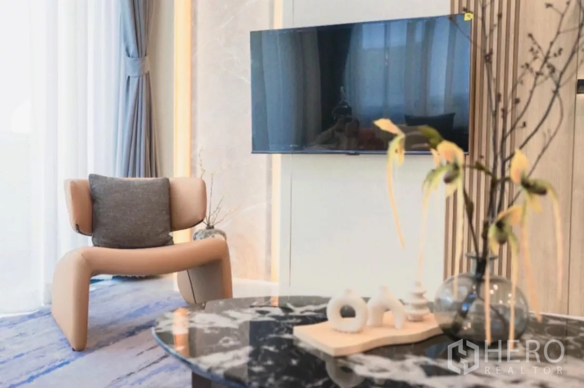 独立式住宅 出租在Bang Phli, Samut Prakan - 温馨休闲角，墙挂电视、设计师单椅与大理石茶几。