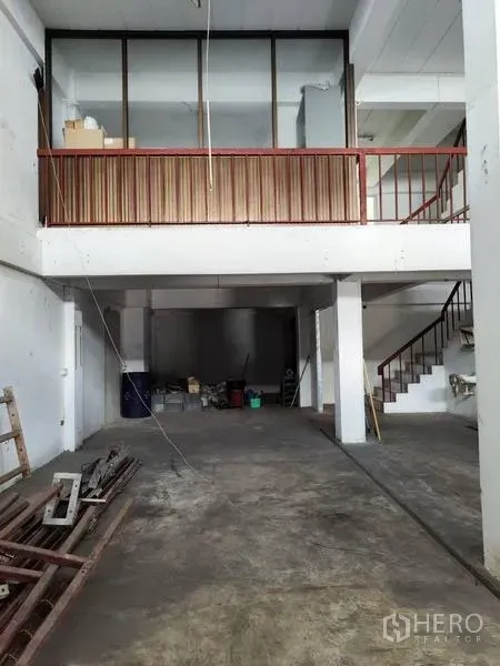 Shophouse for sale in Pathum Thani - Double-height warehouse bay with mezzanine office and staircase.
