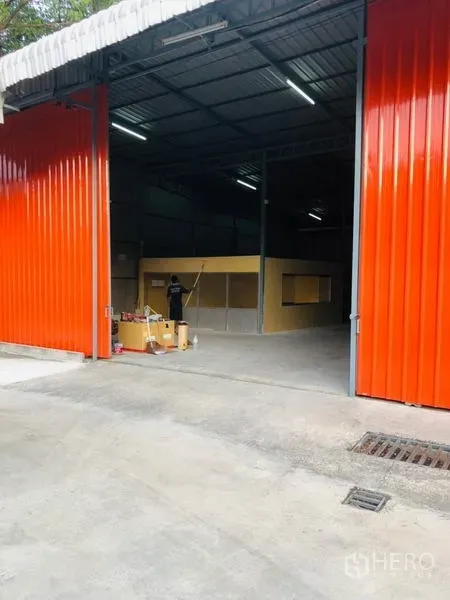 Warehouse for rent in Wang Thonglang, Bangkok - Open red metal doors revealing the loading area and internal office inside the warehouse.