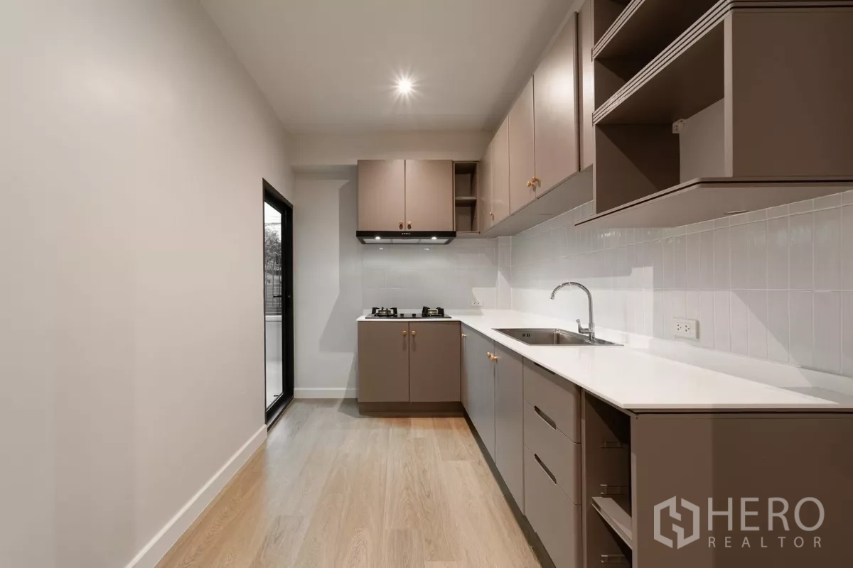 联排别墅 出租在Watthana, Bangkok - 独立泰式厨房，燃气灶、灰褐色柜体，通向服务阳台。