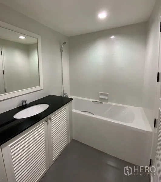 公寓 出租或出售在Watthana, Bangkok - 现代浴室，带浴缸淋浴一体与黑色台面的单盆洗手台。