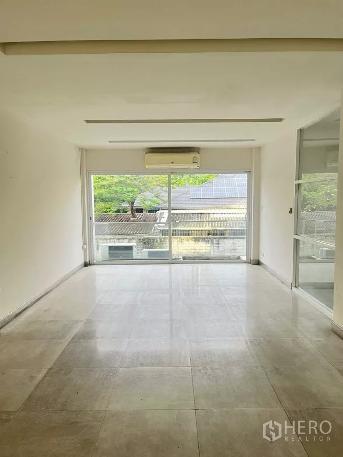 Home Office for rent in Khlong Toei, Bangkok - Bright unfurnished room with large sliding glass doors, air conditioner and green view.