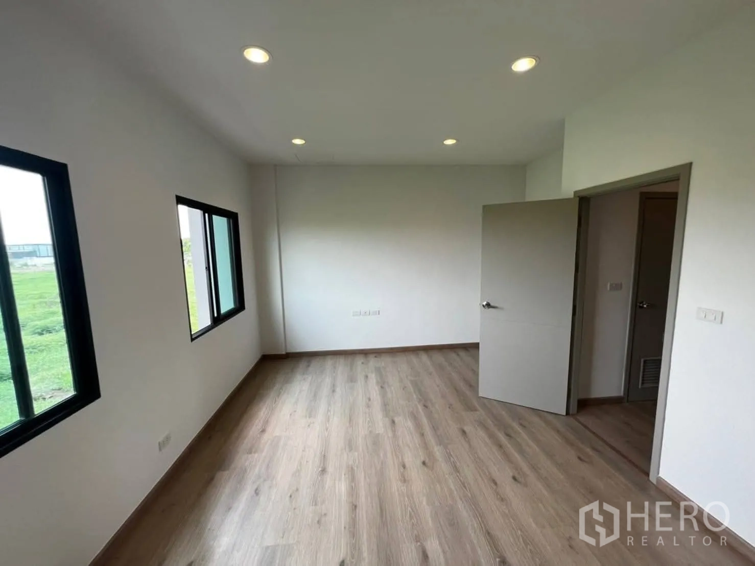 Townhouse for rent in Bang Khen, Bangkok - Corner bedroom with two windows and open green views outside.