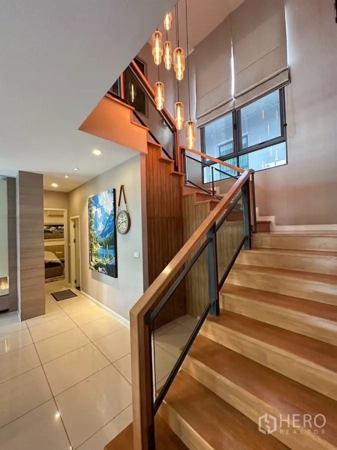 Detached House for sale in Bang Lamung, Chon Buri - Staircase with warm wood treads and designer pendant lighting.