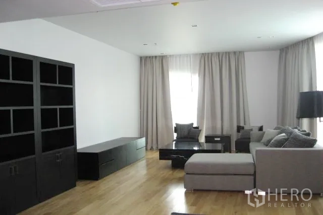 คอนโด ขายในKhlong Toei, Bangkok - ห้องนั่งเล่นกว้าง โซฟาแอลสีเทา ชั้นวางสีดำ พื้นไม้ และผ้าม่านสูง