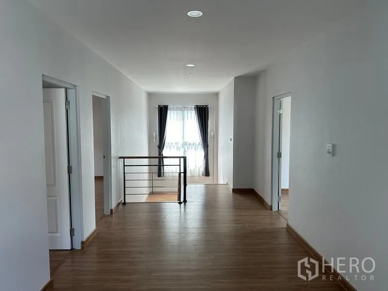 Detached House for sale in Nonthaburi - Upstairs landing and family area with wood floors, railing and doors to bedrooms.
