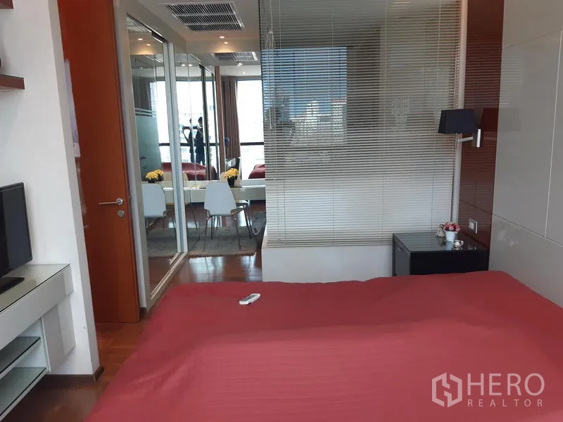 公寓 出租在Khlong Toei, Bangkok - 卧室内景，红色床品、玻璃隔断与镜面衣柜。