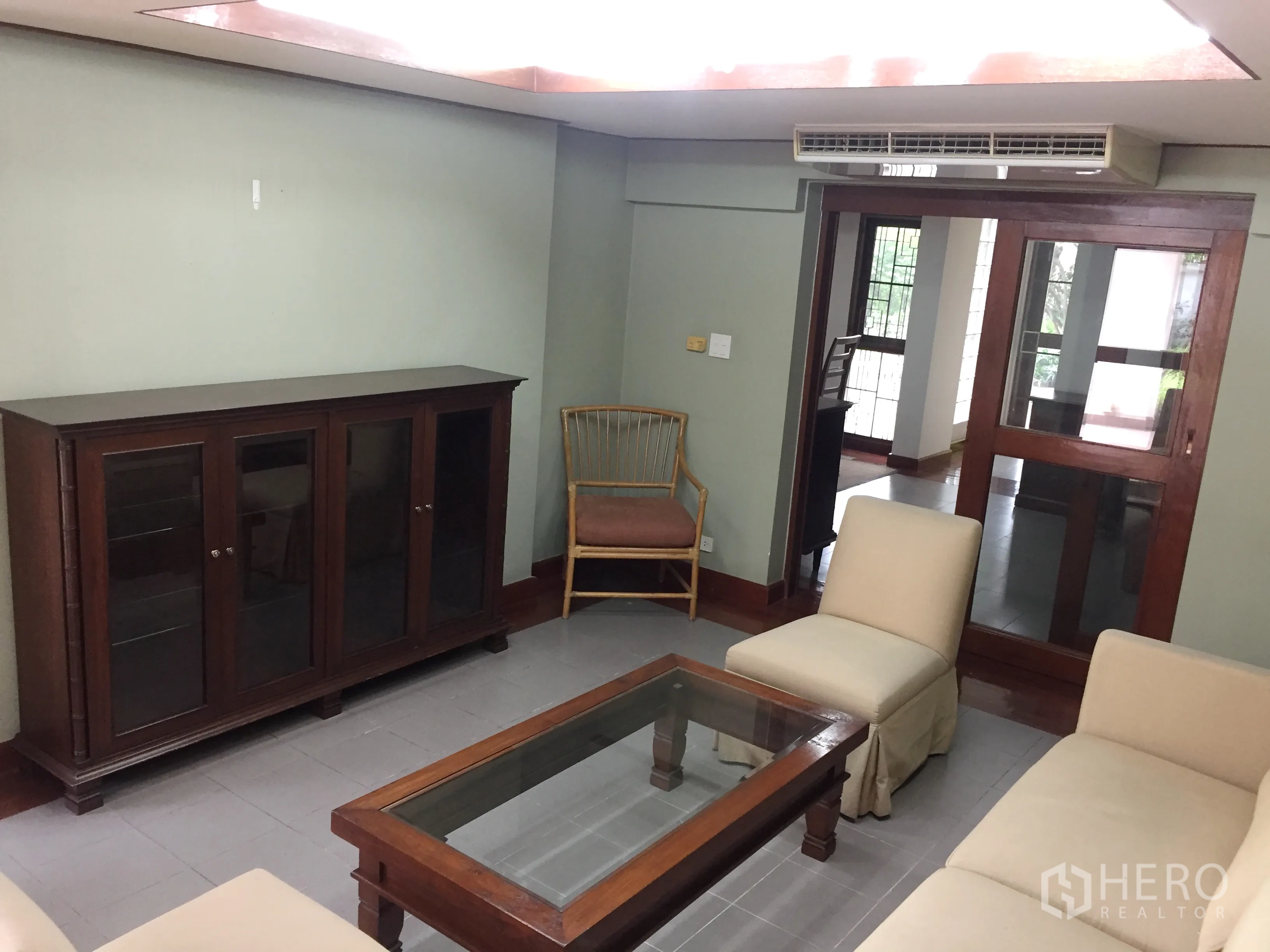 Detached House for rent in Khlong Toei, Bangkok - Cozy living room with sliding glass doors and wood-framed display cabinet.