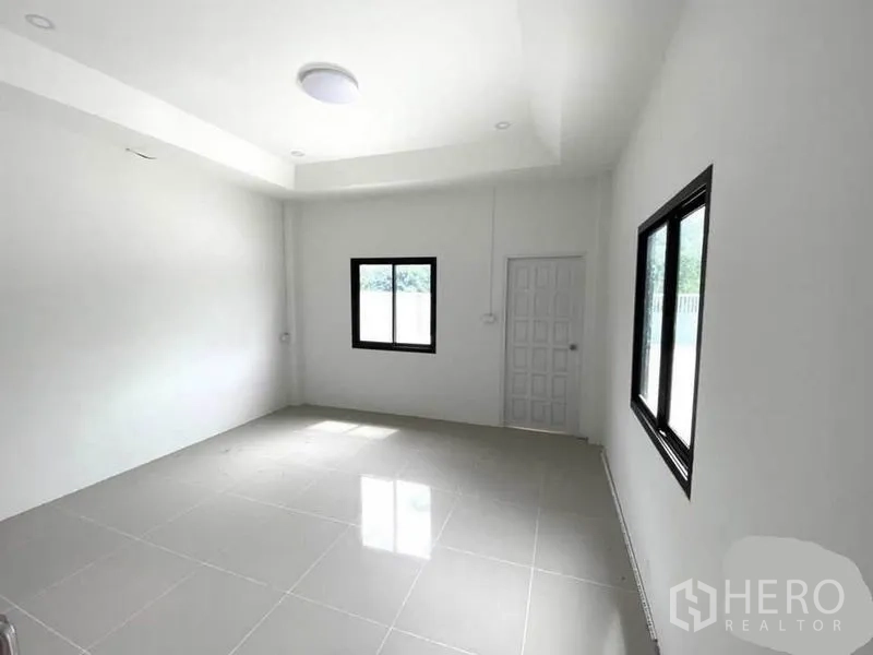 Warehouse for rent in Lat Lum Kaeo, Pathum Thani - Clean white office room with glossy tile floors and two black-framed windows.
