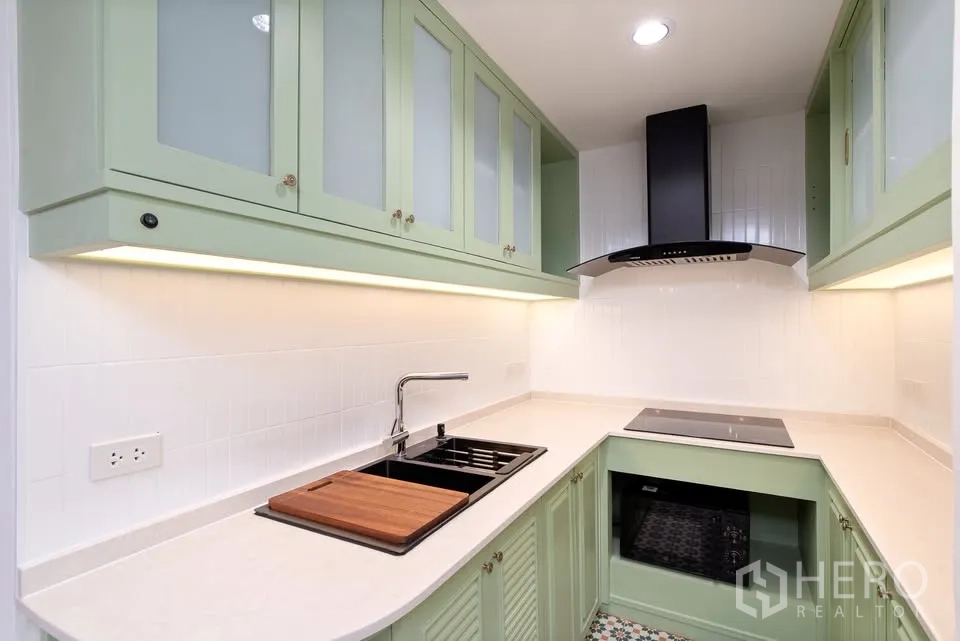 คอนโด for rent in Watthana, Bangkok - ครัวรูปตัวแอลตู้สีเขียว เตาไฟฟ้า และเครื่องดูดควัน.
