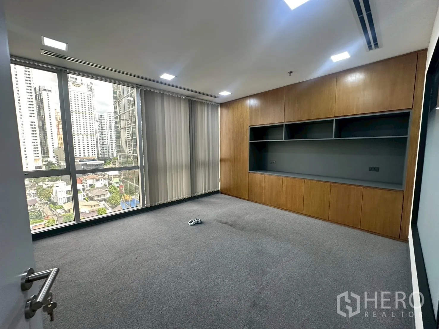 Office Space for rent - Executive office with city-facing window and full-length wooden storage.