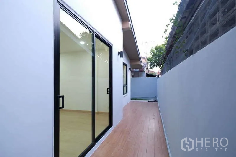 独立式住宅 出售在Bueng Kum, Bangkok - 房屋侧边木质步道，推拉玻璃门与私密围墙