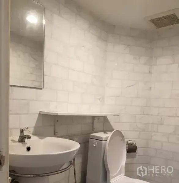 零售空间 出租在Bang Rak, Bangkok - 现代卫浴，白色大理石纹墙面、挂墙式洗手盆与坐便器。