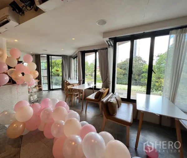 零售空间 出租在Watthana, Bangkok - 转角座位区配落地窗与自然采光，搭配活动气球与皮质长椅。