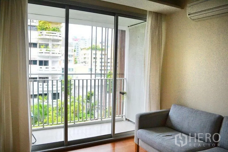 คอนโด ให้เช่าในWatthana, Bangkok - พื้นที่นั่งเล่นโซฟาสีเทา เปิดออกสู่ระเบียงผ่านประตูกระจกบานเลื่อน