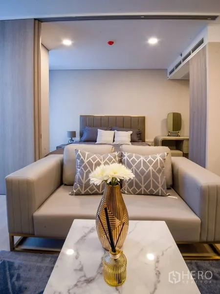 คอนโด ให้เช่าในKhlong Toei, Bangkok - โซฟาพร้อมโต๊ะกลางหินอ่อน มุมมองไปยังห้องนอนหัวเตียงบุผ้า