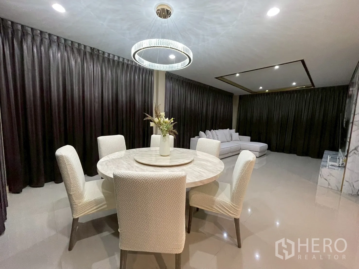 Detached House for rent in Bang Kapi, Bangkok - Dining area with a round table for six beneath a contemporary chandelier.