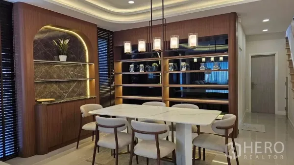Detached House for rent in Bang Phli, Samut Prakan - Dining area with marble-top table, six chairs and warm wood built-in shelving.