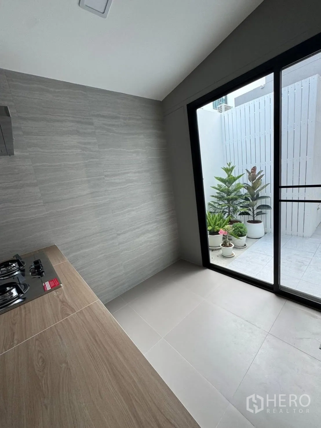 ทาวน์เฮาส์ for rent in Bang Phli, Samut Prakan - ครัวปิดผนังกระเบื้องเทา เตาแก๊ส และประตูกระจกออกลานบ้าน