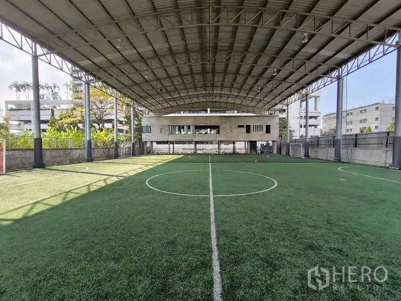 Warehouse for rent in Huai Khwang, Bangkok - Covered futsal-size artificial turf field beneath a high steel roof.