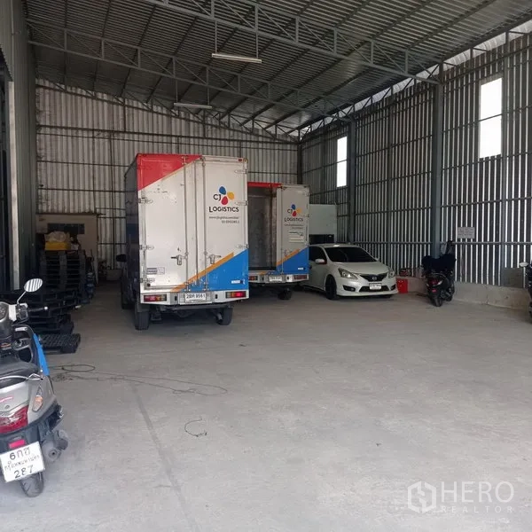 คลังสินค้า ให้เช่าในBang Kapi, Bangkok - ภายในโกดังหลังคาสูง ผนังเมทัลชีท มีรถบรรทุกและรถยนต์จอดบนพื้นคอนกรีต