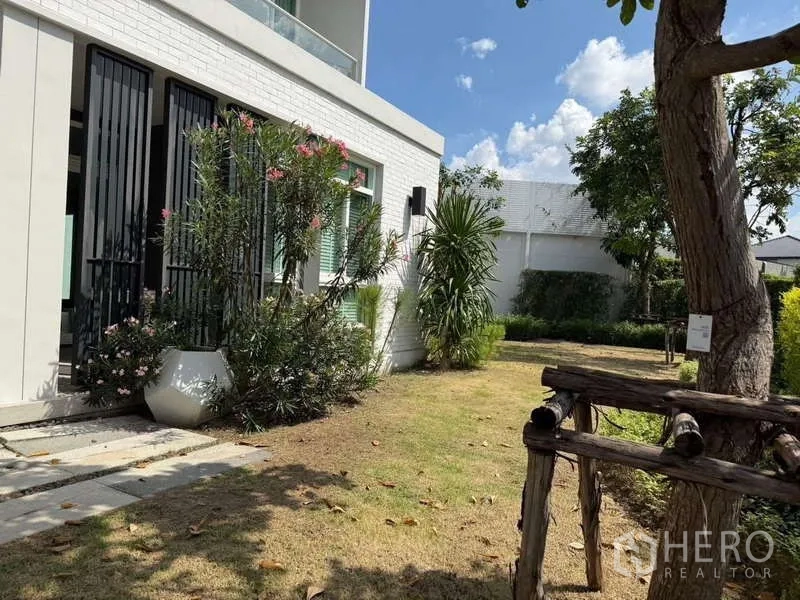 Detached House for rent or sale in Bang Bua Thong, Nonthaburi - Garden corner beside the house with potted plants, vertical louvers, and shaded lawn.