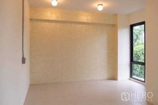 Office Space for rent or sale in Lak Si, Bangkok - Bright cream-toned room with a corner window overlooking trees.