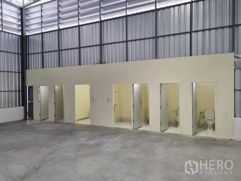 Warehouse for rent in Khlong Sam Wa, Bangkok - Warehouse interior with a row of restrooms, concrete floor, and high ventilated steel roof in Khlong Sam Wa.