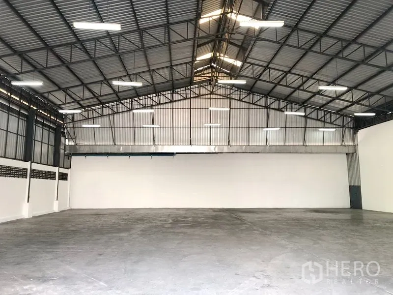 Warehouse for rent in Pak Kret, Nonthaburi - Clear-span warehouse floor with white walls, skylights, and ample ceiling lights for operations.